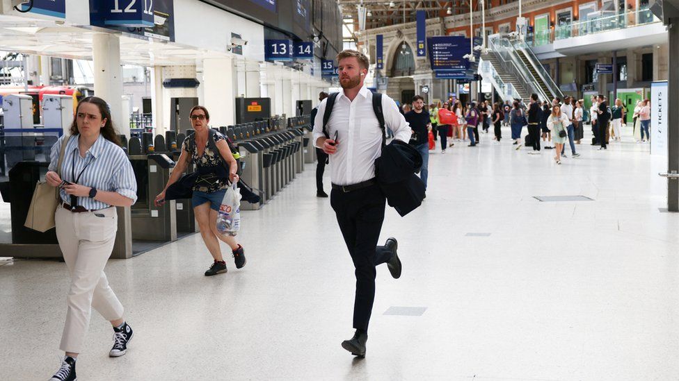 Passengers run to catch a train at Waterloo station before train service ends early