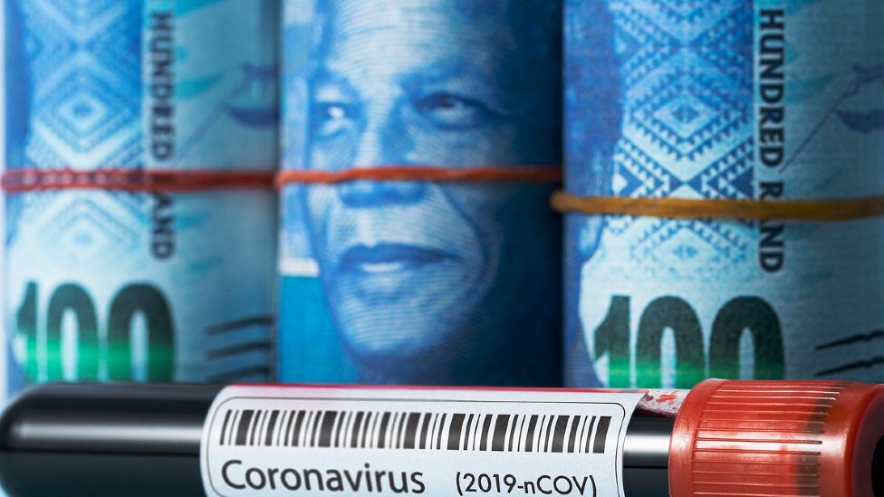 Bundles of South African rand notes showing the face of Nelson Mandela placed behind a vial of blood laballed coroanvirus