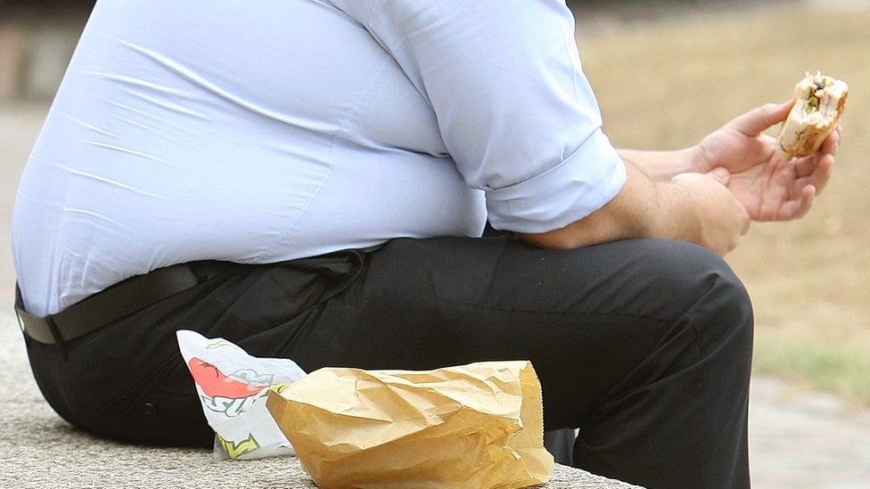 Obese man eating a sandwich