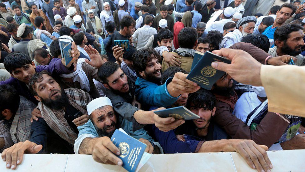 A crowd of men holding up their passports