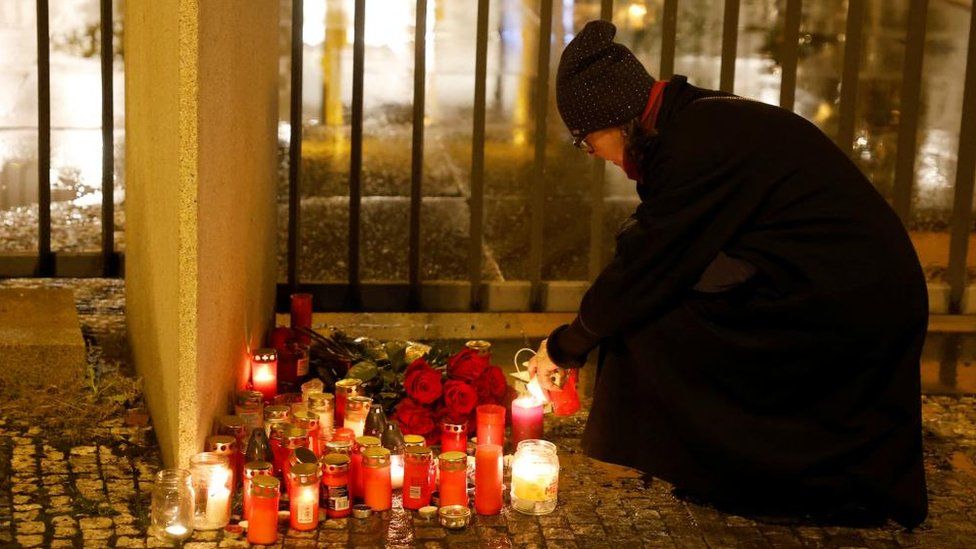 A woman lights a candle at the scene of a shooting in Charles University in central Prague