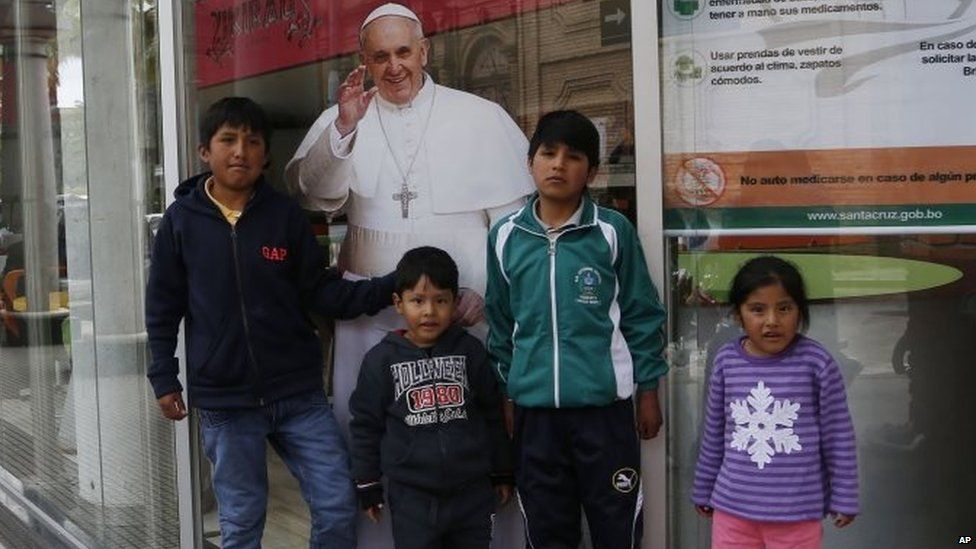 Children pose for a pictures with a life-size cut-out poster of Pope Francis on 5 July, 2015.