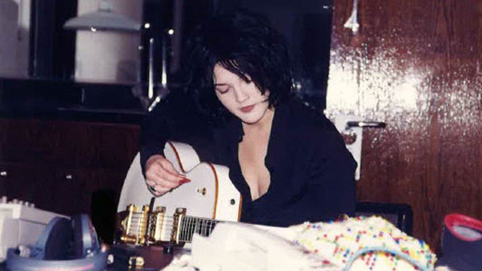 A photograph of actress Drew Barrymore playing the guitar