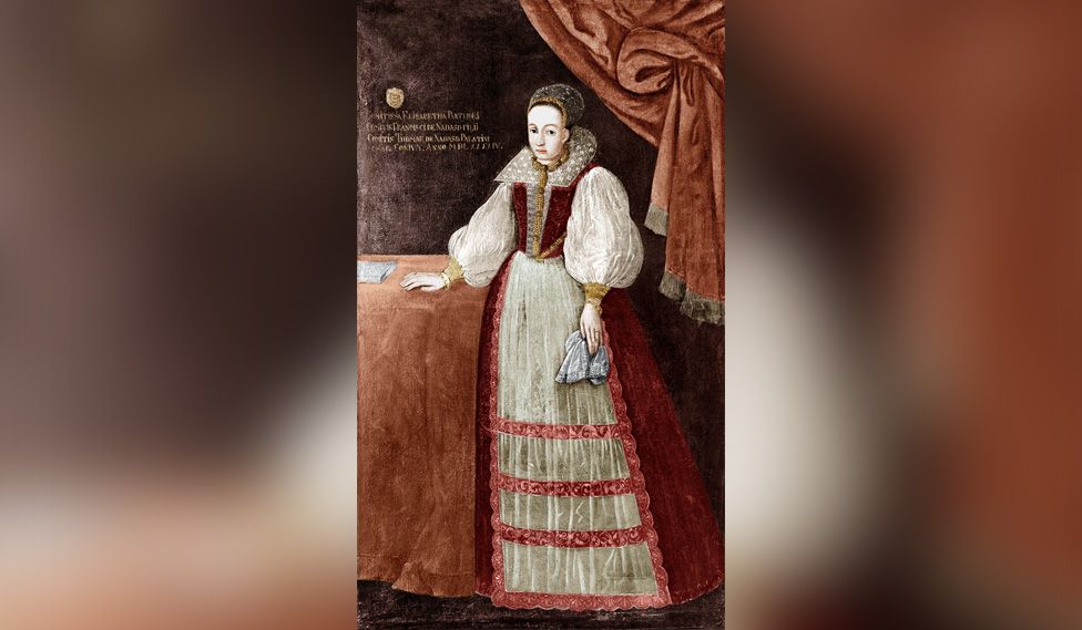 Elizabeth Bathory shown in a painted portrait. She is holding a cloth in one hand and the other rests on a table
