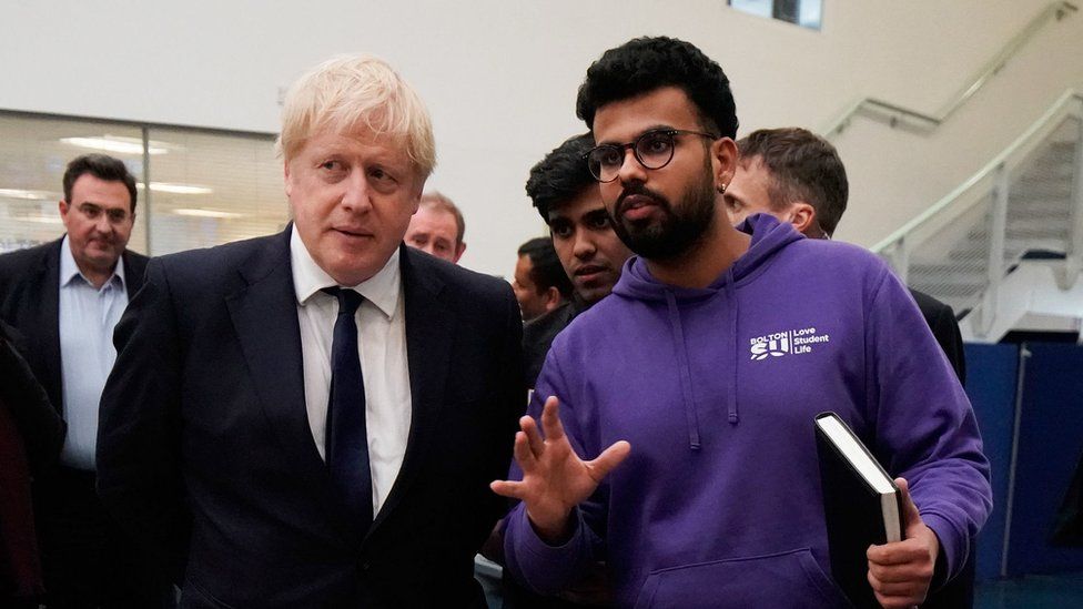 Prime Minister Boris Johnson speaks to a student during a visit to Bolton University chancellors building after a huge blaze