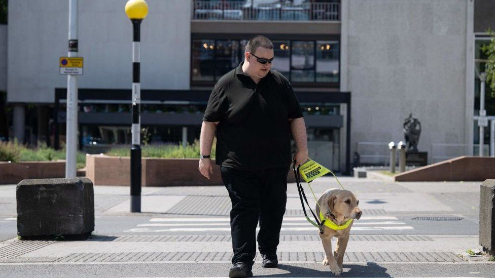 A visually impaired person with their guide dog