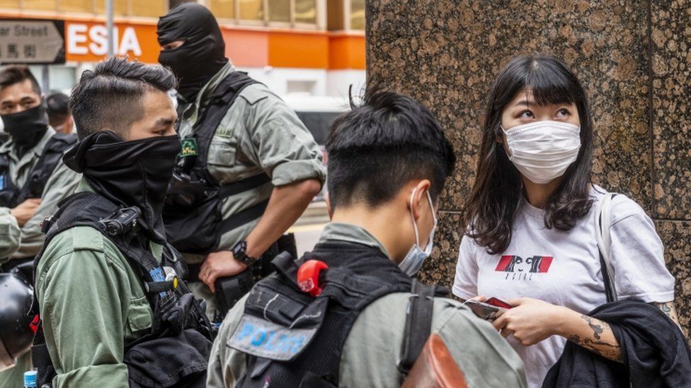 A woman is questioned by Kong Kong riot police