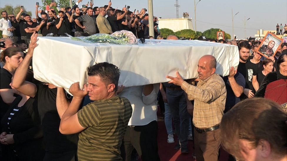 Iraqi Christians carry the coffin of fire victims during a mass funeral in al-Hamdaniya, 27 September 2023