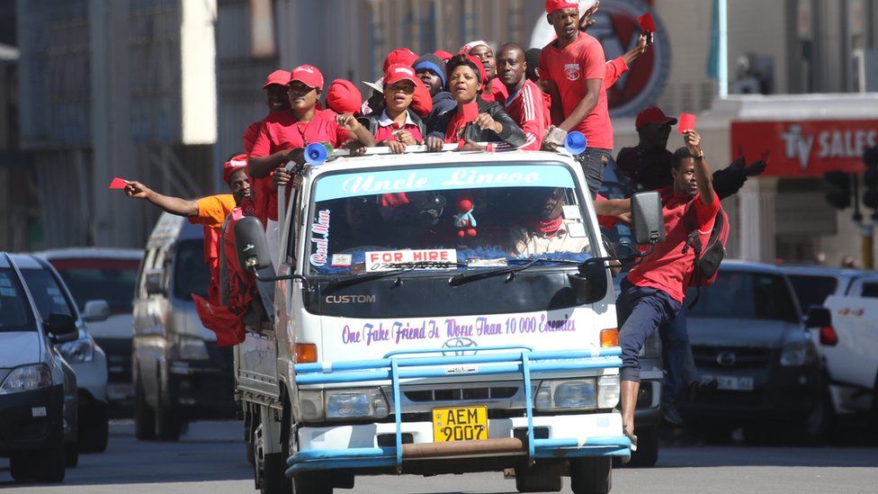MDC supporters dressed in red hang from a vehicle during a protest in Harare, Zimbabwe - Wednesday 11 July 2018