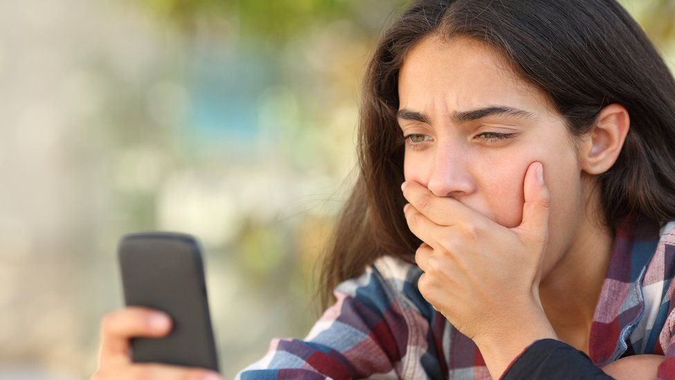 A worried-looking teenager looking at mobile phone