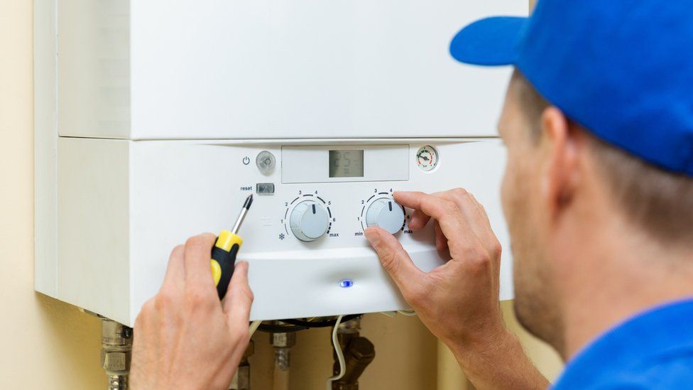 Worker sets up central gas heating boiler at home