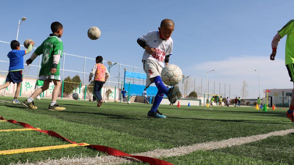 A boy juggles the ball on a football field