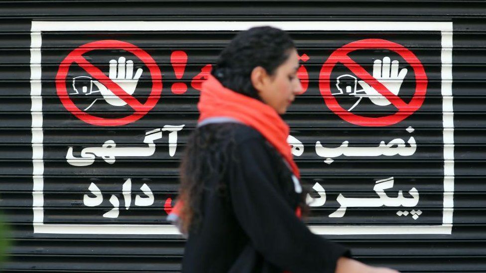 An Iranian woman walks next to a closed shop without wearing a headscarf, in Tehran, Iran, 10 August 2023