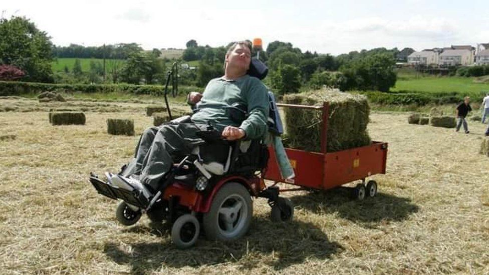 Jonathan Turtle uses his wheelchair to tow a trailer containing hay bales