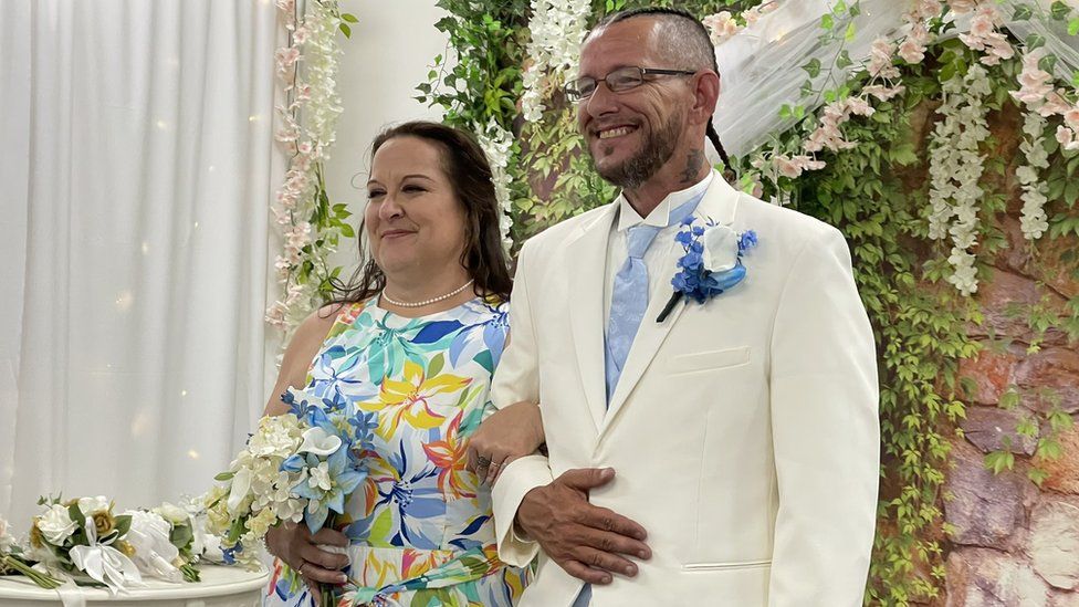 Женщина и мужчина улыбаются на своей свадьбе.