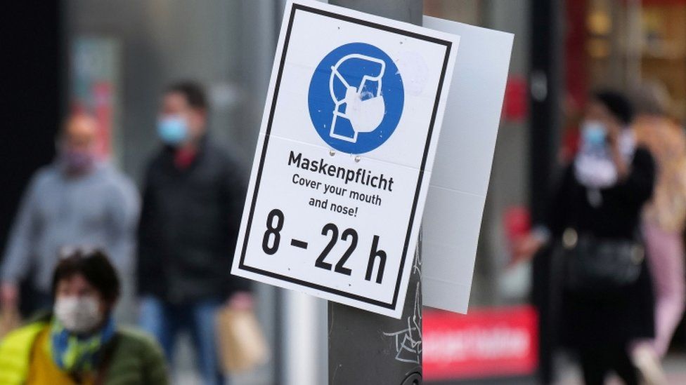 People walk past a sign reading "Mask is mandatory" on a shopping street as the spread of coronavirus disease continues in Frankfurt, Germany, October 19, 2020