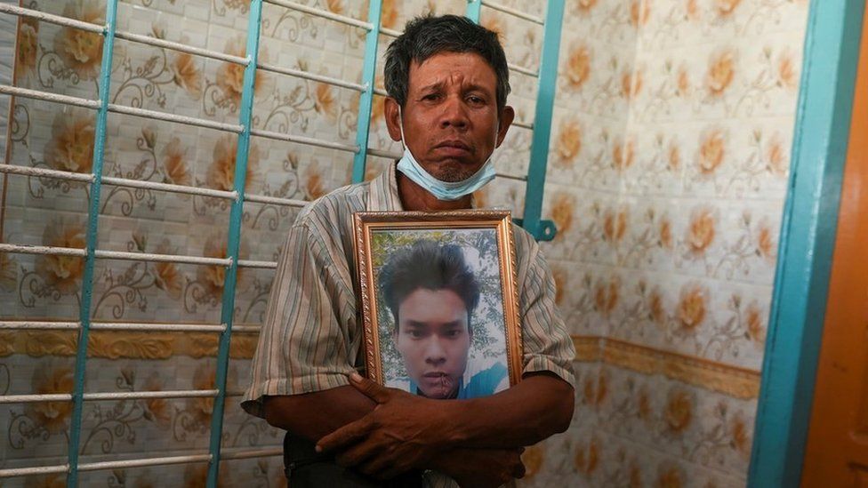 Мужчина держит фотографию жертвы, застреленной во время акции протеста против переворота на кладбище на окраине Янгона, Мьянма, 5 марта 2021 года. REUTERS / Stringer