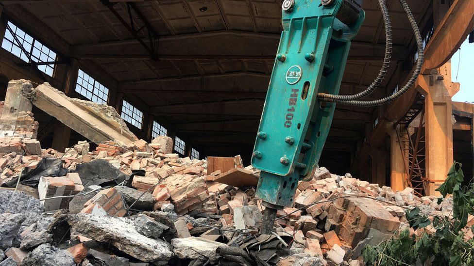 An excavator is seen on the debris in front of the demolished building of Chinese artist Ai Weiwei's art studio