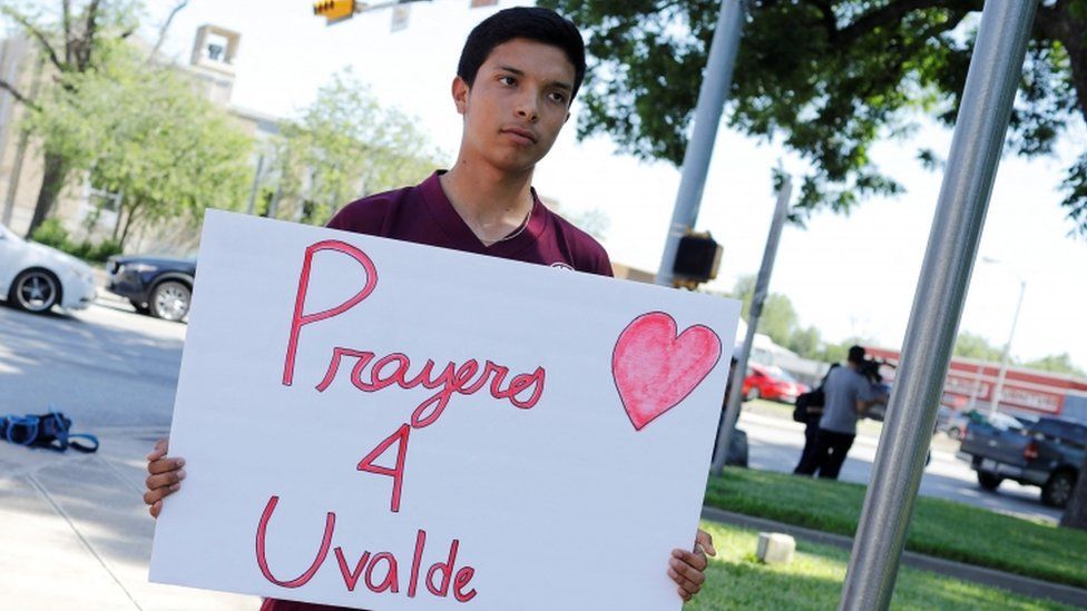 Luis Esquivel holds a sign saying 'Prayers 4 Uvalde' at the town square in Uvalde on 25 May