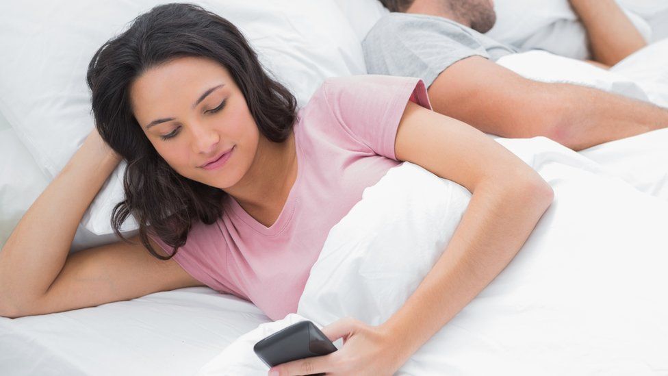 woman in bed on phone