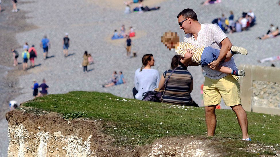 A man was spotted lifting a child o peer over the cliff edge at Seven Sisters