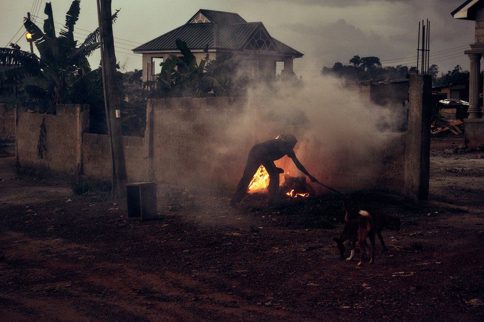 A man lights a fire in Kumasi, Ghana