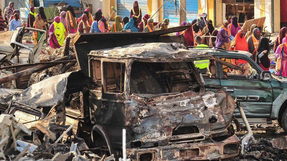 People gather near burnt vehicles a day after a truck bomb exploded in the centre of Mogadishu
