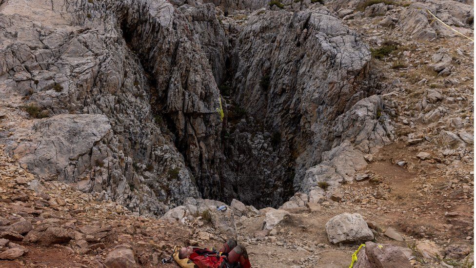 A rescuer rests at the entrance of Morca Cave as he takes part in a rescue operation to reach