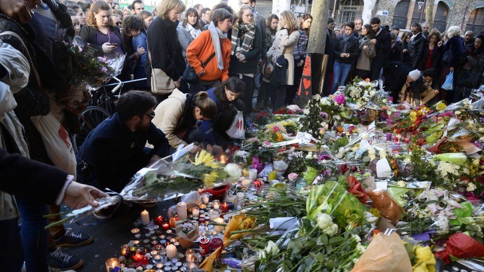 People gather at a makeshift memorial site on November 15, 2015, outside of the La Belle Equipe cafe