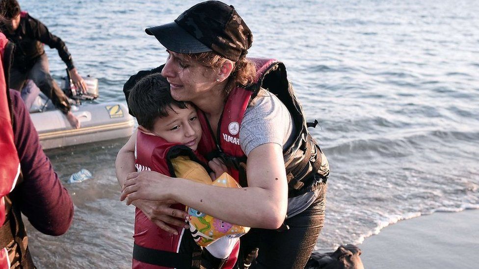A migrant woman hugs her son after safely arriving to the shores of the Greek island of Kos on 18 August 2015