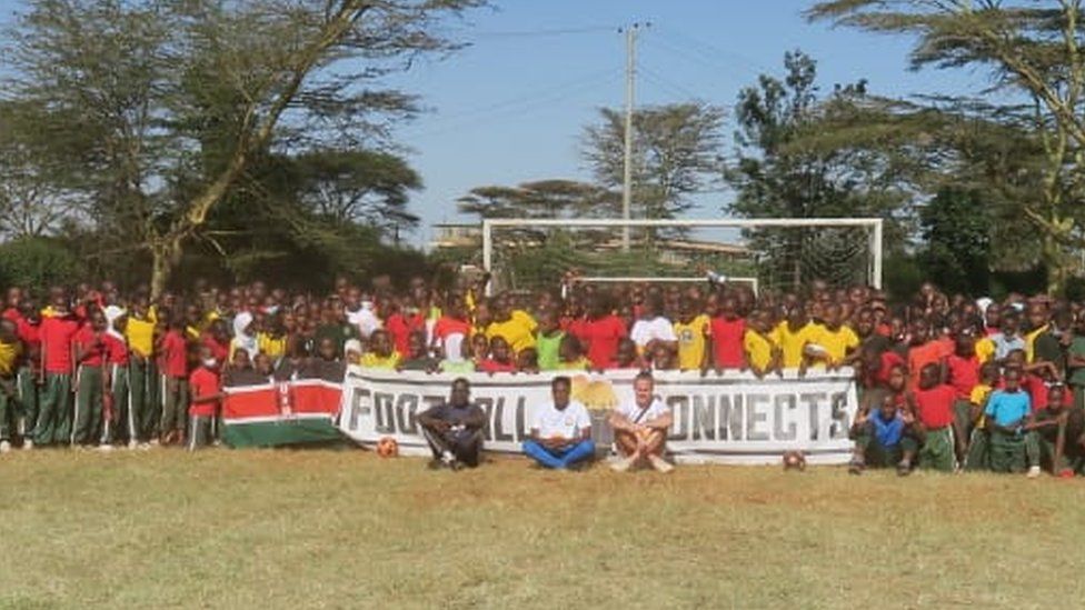 a crowd celebrate the completion of the football pitch in Kenya