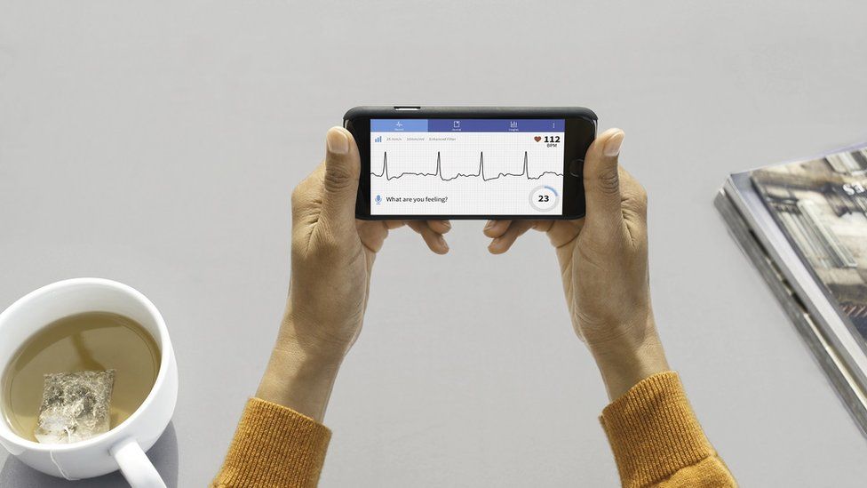 Woman holding smartphone with heartbeat chart on screen