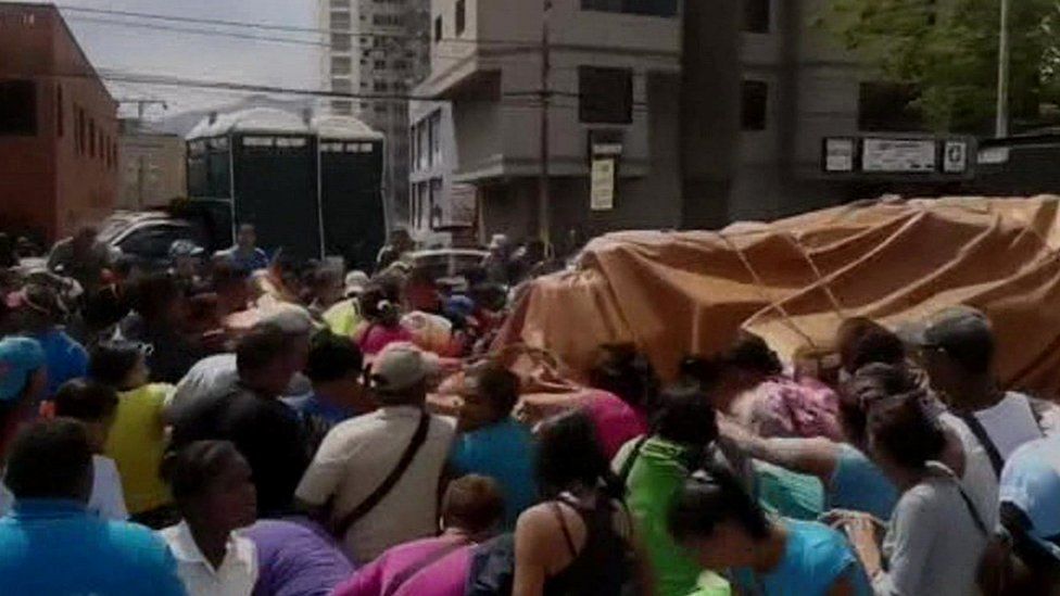 People surround a truck delivering flour in Puerto la Cruz