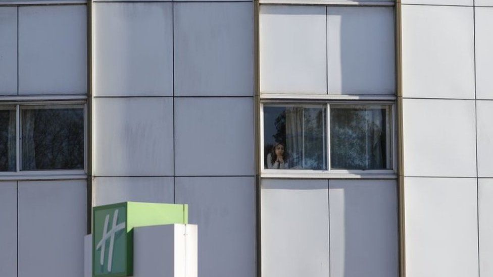 A person stares out of a hotel window near Heathrow in west London in March 2020