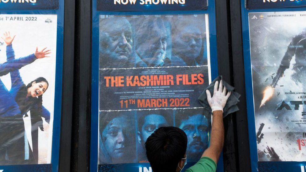 In this picture taken on April 7, 2022, a worker cleans a display with the poster of the Bollywood movie 'The Kashmir Files', outside a cinema hall in New Delhi.