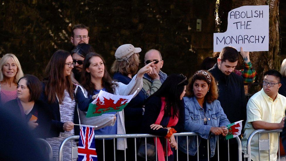 A crowd with one man holding a 'Abolish the monarchy' sign