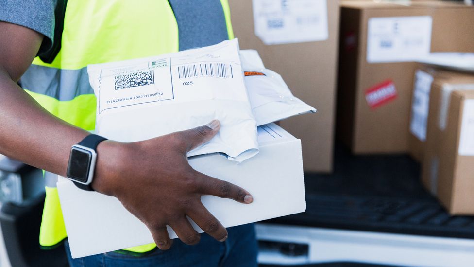 A close up of a delivery driver holding a parcel