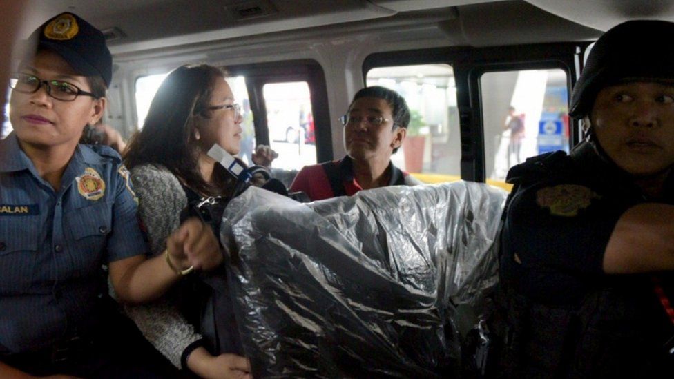 Maria Ressa being driven away in a police car on March 29