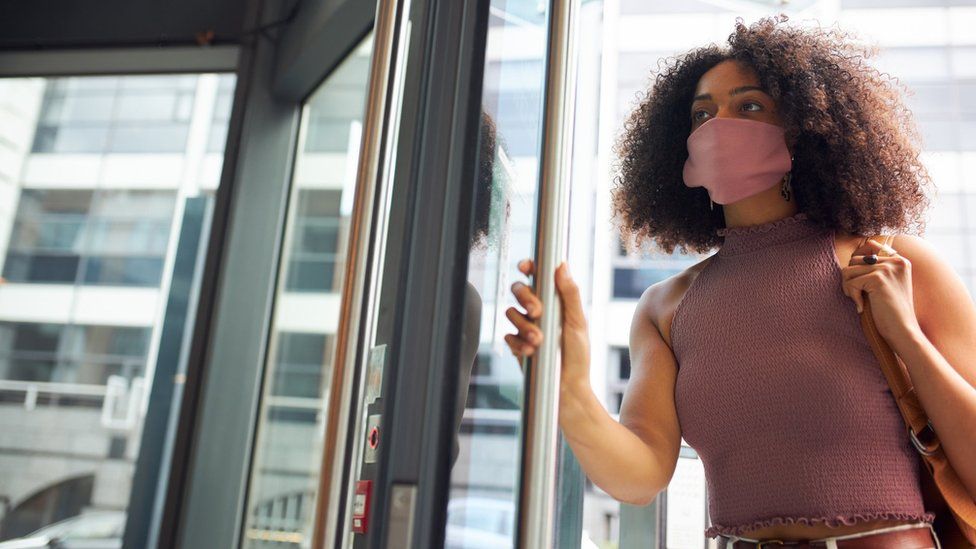 Young woman entering office wearing face mask