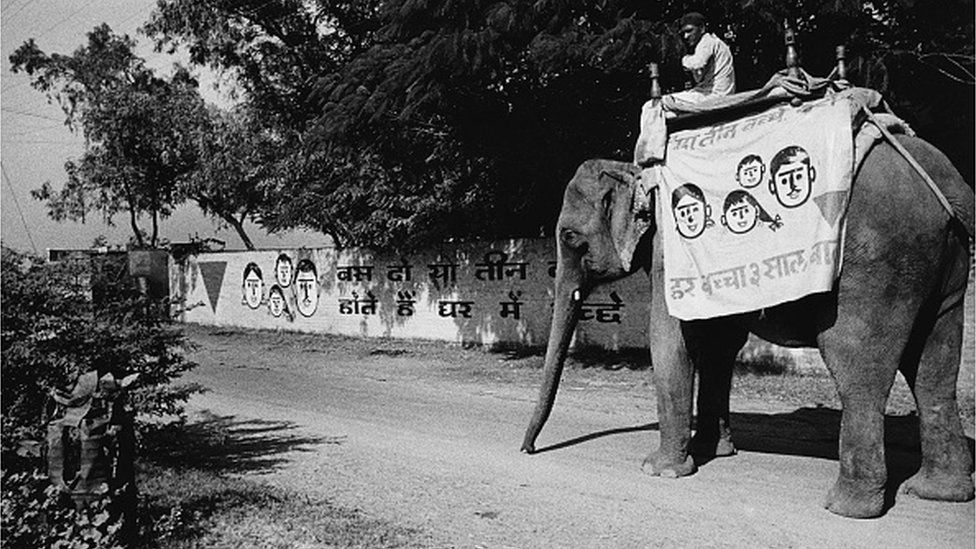 An elephant bearing the red triangle symbol of the Lal Tikon Fund to publicise birth control and family planning, enters a village