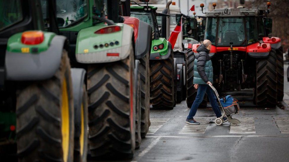 A man walks past tractors blocking a road on the fourth consecutive day of protests in Pamplona, Spain, 09 February 2024