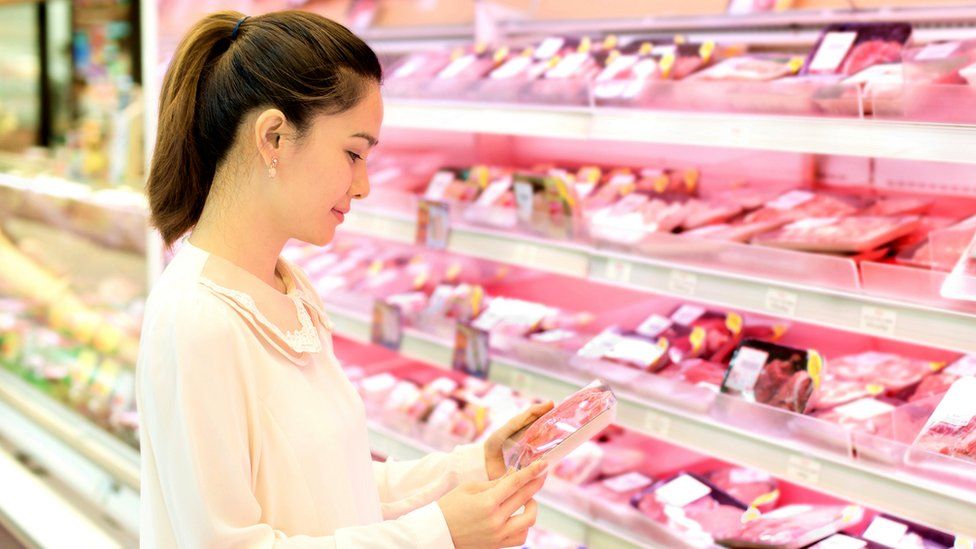 Женщина покупает мясо в супермаркете