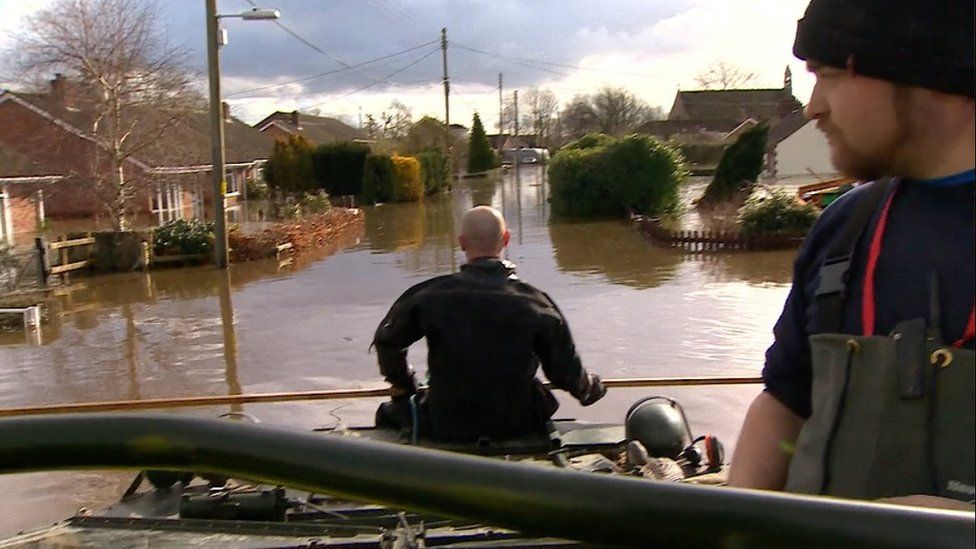 Rescuers travel up flooded street in boat