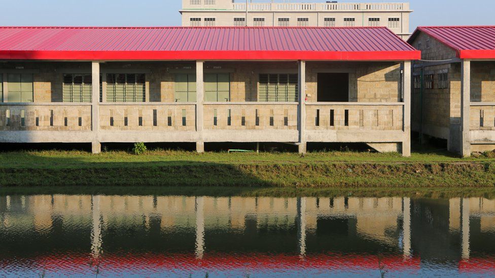 A single red roofed house reflects its bright colours into a pool of water