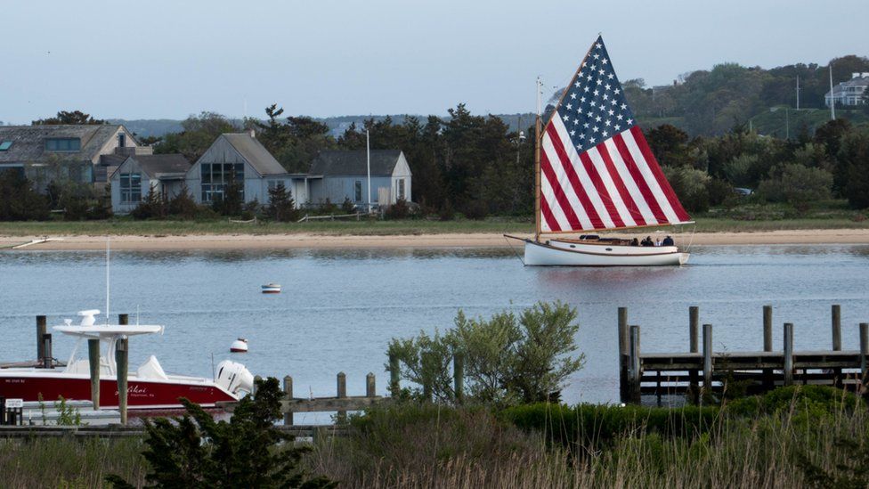 Sailboat with American-flag sail leaves Edgartown harbor, Marthas Vineyard, Massachusetts