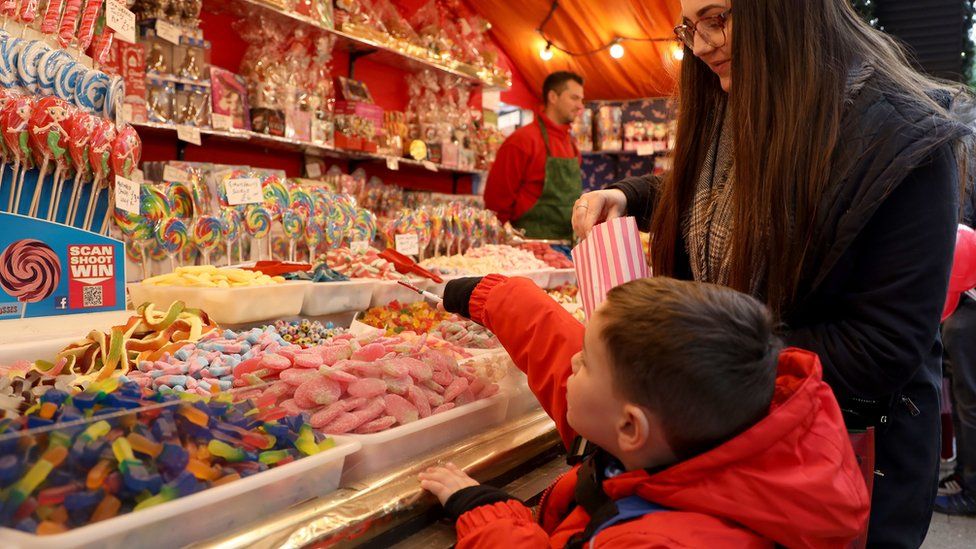 small child reaches for candy at Belfast Christmas market