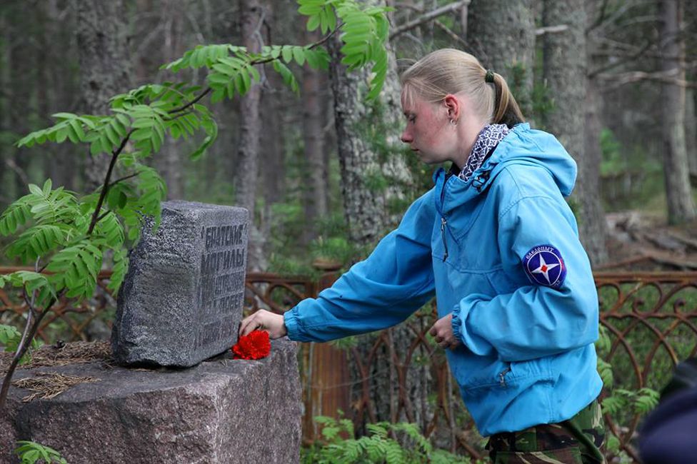 Marina Titova lays a carnation on a grave stone on Mudyug Island