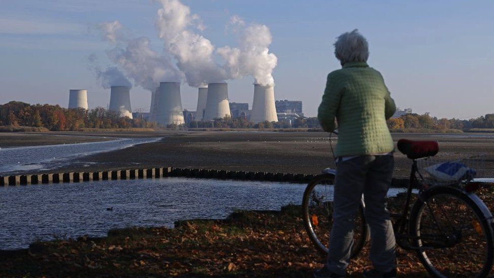 Woman stands in front of a coal plant in Germany