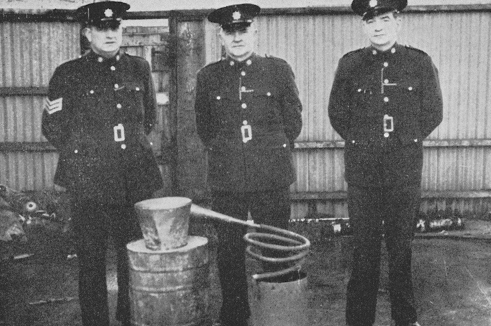Police officers stand next to a confiscated poitin still in the 20th Century
