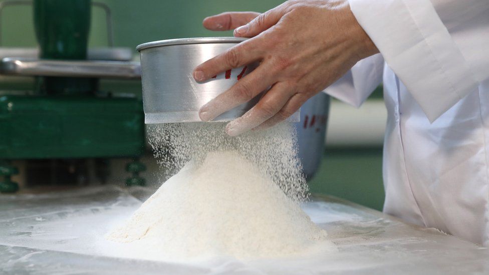 A man sifting flour onto a table